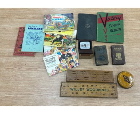 Two cribbage scoring boards and a vintage road atlas, vintage stamp collection, two vintage savings boxes, 1950's tv money bo