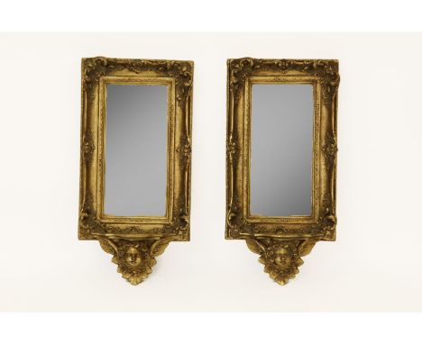 A pair of gilt framed mirrors, the pieced frame decorated in relief with scrolling foliage and a shelf to the bottom supporte