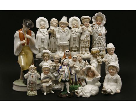 A large collection of porcelain fairing figures, the largest being a piper leaning against a tree trunk, 27 cm high