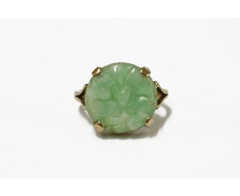 A carved jade plaque ring, a circular carved jade plaque of a moth design, claw set to a plain polished shank (tested and val