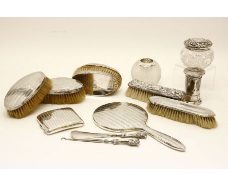 A Quantity of silver backed brushes, a silver backed mirror, a silver topped jar, a silver mounted match striker, cigarette c