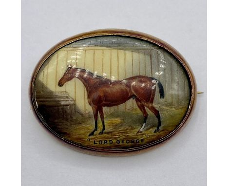 An enamel brooch of a racehorse 'Lord George' set in 18 ct gold with safety chain (Total weight 17.8g)
