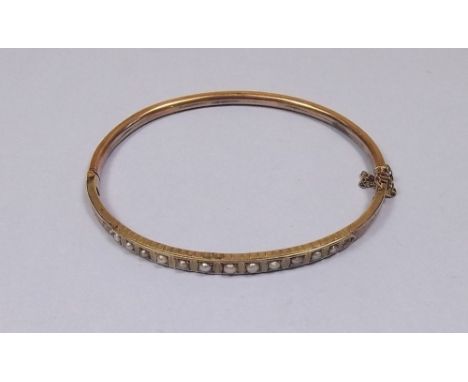 An Edwardian 9 carat gold hinged bangle set pearls