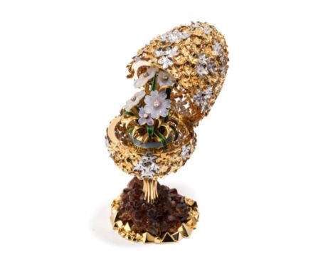 A GOLD AND GEM-SET SURPRISE EGG ON STAND, STUART DEVLIN, LONDON, 1977 the openwork body of white and yellow gold flowerheads 