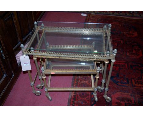 A metal and glass topped nest of three occasional tables, raised on roller castors