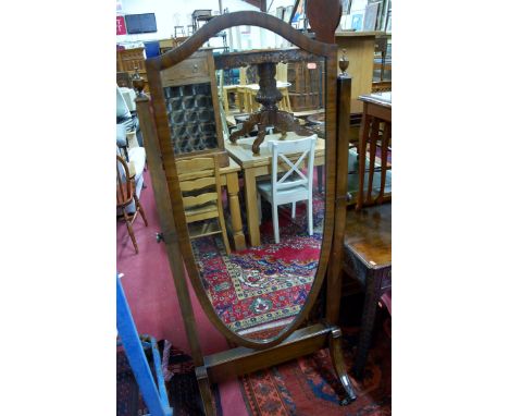 A Regency style mahogany shield shaped cheval mirror raised on outswept supports to brass capped castors, width 68cm