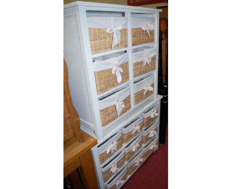 A white painted three-tier open bakery shelf with removable wicker baskets, together with one other slightly smaller example 