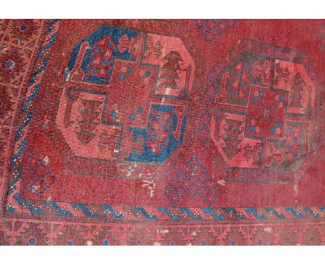 A Persian woollen Bokhara rug, the rust coloured ground decorated with three rows of large medallions within trailing borders