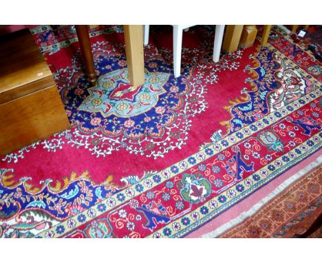 A Caucasian woollen carpet, the red ground having a centre medallion issuing scroll flowers and foliage within trailing traml