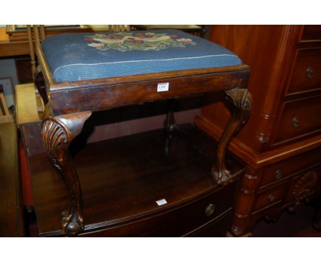 A Georgian style joined walnut dressing stool, having a floral tapestry upholstered inset top and raised on shell capped cabr