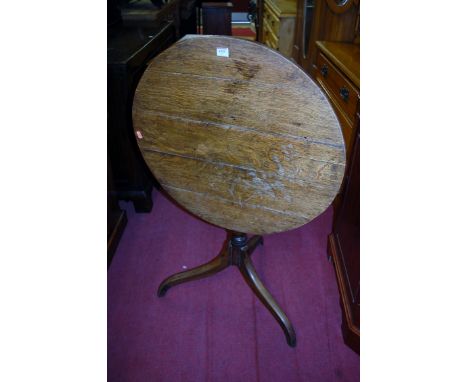 An early 19th century provincial oak circular tilt-top pedestal tripod table