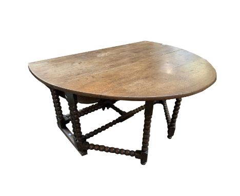 A large oak oval bobbin turned double gateleg dining table, early 18th century, with a single frieze drawer on sled base, hei