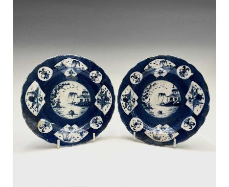 A pair of Bow powder blue ground plates, circa 1765, with lobed rims, each painted with oriental lake landscapes and floral s