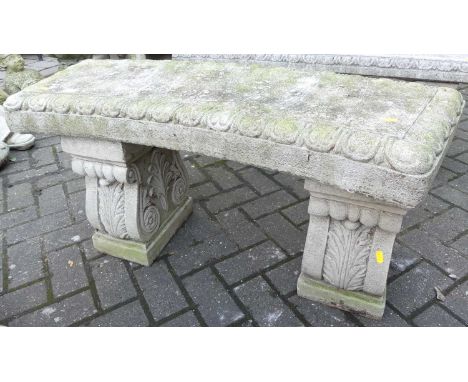 A reconstituted stone two-seater slightly curved garden bench seat, raised on scroll floral pedestal end supports, length 104