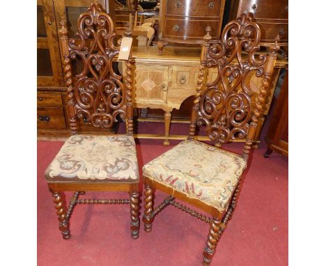 A pair of mid-19th century rosewood hall chairs, each having intricate floral carved scroll and pierced backs, spiral and bob