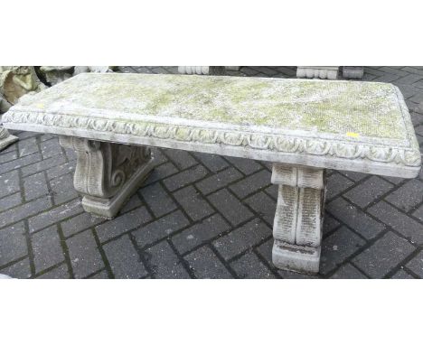 A reconstituted stone two-seater garden bench seat, raised on floral scroll pedestal end supports, length 114cm