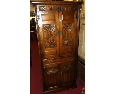 An Old Charm oak free standing drinks cabinet, having an arrangement of four doors and central pull-out slide, width 83cm