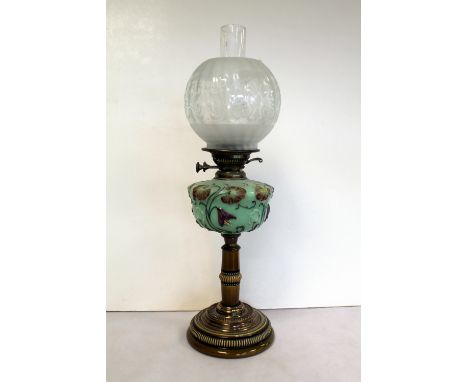 Victorian oil lamp, the opaque green glass reservoir with moulded polychrome floral decoration, on pottery column and circula