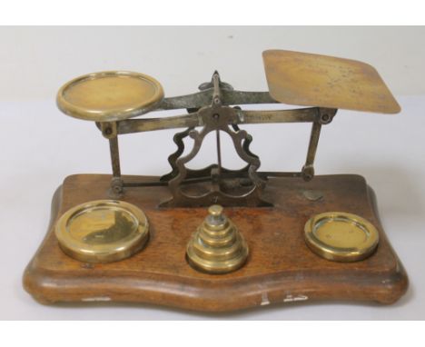 Set of Victorian brass postal scales on oak base with graduated weights 1lb to ½oz. 27cm wide.