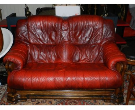 A 20th century two-seater red leather sofa, having an oak frame. 
