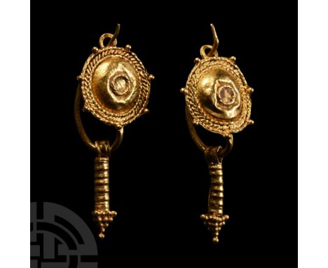 1st-2nd century A.D.. Matched pair, each a wire hoop with hook-and-eye closure, domed shield with central filigree ring, radi