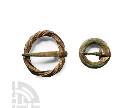 13th-14th century A.D.. Comprising a gilt-bronze ring brooch with segmented face to the hoop, and a larger ring brooch with t