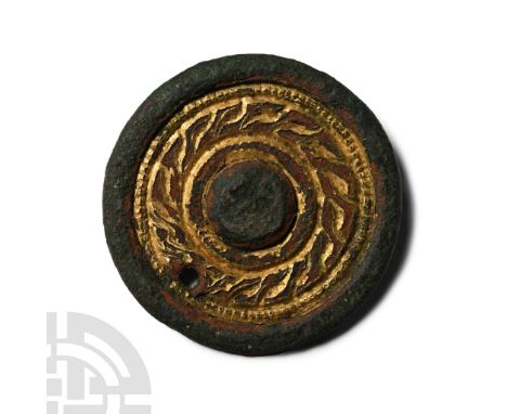 6th century A.D.. Discoid with raised rim and central roundel, band of gilt knotwork ornament surrounding; later pierced for 