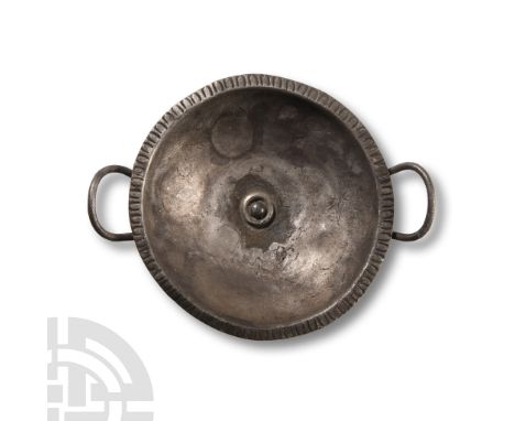Circa 4th-5th century A.D.. Comprising a shallow bowl fitted with handles and raised foot, the rim engraved with petals. Cf. 