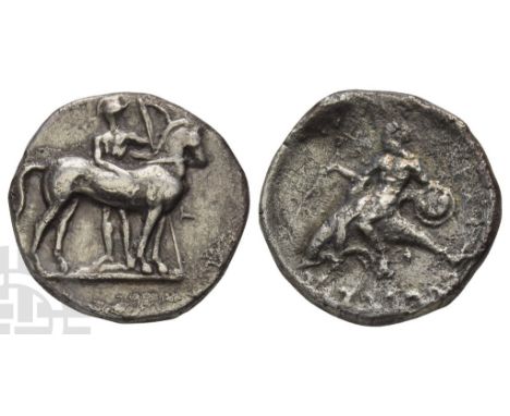 Circa 344-340 BC.. Warrior, nude but for helmet, standing facing behind bridled horse to left, holding spear and shield with 