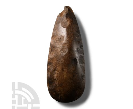 Neolithic Period, circa 4th-3rd millennium B.C.. With pointed butt and broad curved cutting edge; even chocolate-brown patina