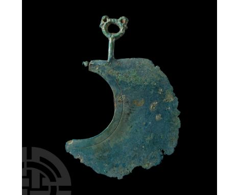 9th-8th century B.C.. Comprising a broad crescentic plate with incised border and radiating hatched triangles respecting the 