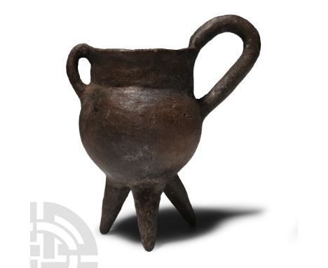 Early Bronze Age, 2300-2000 B.C.. With bulbous body, broad mouth, three radiating legs, small loop handle to the rim and larg