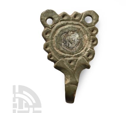 Circa 6th century A.D.. D-shaped tag with hook to the apex and pierced lugs above ring-and-dot motif surrounded by pellets.  