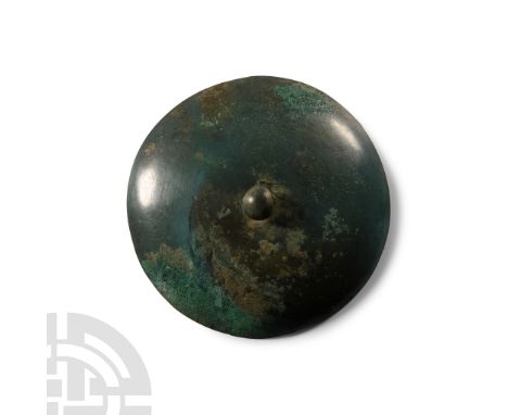 1st millennium B.C.. Broad convex plaque with central button finial, ring to the underside. Cf. similar items in the British 