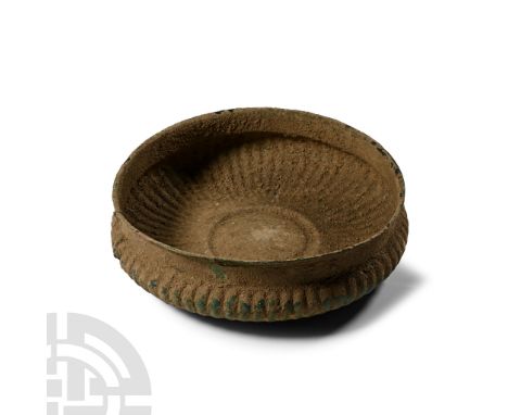 6th-4th century B.C.. A broad carinated bowl with radiating repoussé panels, central roundel, carination below the rim; crack