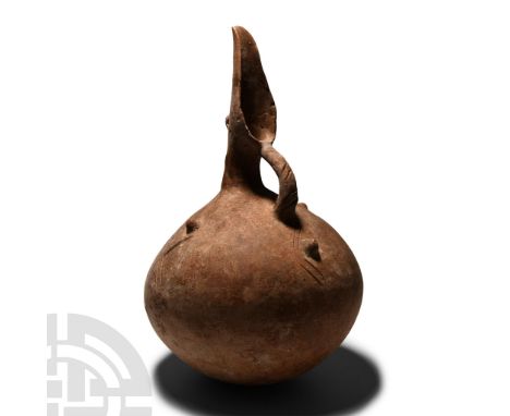Middle Bronze Age, circa 2000-1800 B.C.. Of globular profile with strap handle and tall scooped spout; applied lugs to the sh