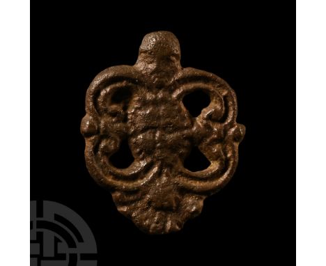 15th century A.D.. Openwork fitting with central mask and scrolled loops, attachment hooks to the reverse.  7.8 grams, 32 mm 