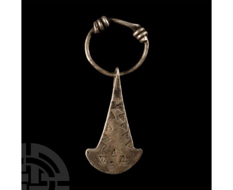 Circa 8th-11th century A.D.. Tapering axehead pendant on a ring with coiled ends, triangular punched detailing.  3.75 grams, 