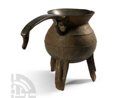 14th century A.D.. Shaped as a small cauldron with a long curved handle decorated with five incuse circles extending from the