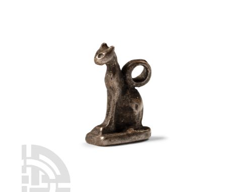 Late Period, 664-332 B.C.. Modelled seated on a tongue-shaped base, with facial detailing and suspension loop to the back. Cf