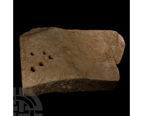 Circa 2nd millennium B.C.. Rectangular worked stone block with one irregular edge; the thicker, dressed edge with a group of 
