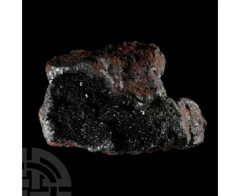 A large specimen with an internal cavity, displaying steel grey, reddish brown, grey black, and black colours, collection num