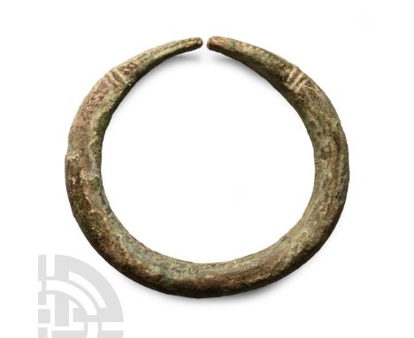 13th-7th century B.C.. Round-section substantial shank with flattened ends, low-relief ribbed collars, snake-head detailing. 