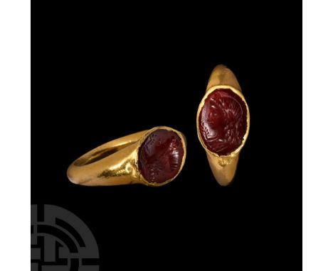 1st century A.D.. Hollow-formed shank with inset ellipsoid garnet cloison intaglio bust of Apollo with frond and laurel-leaf 