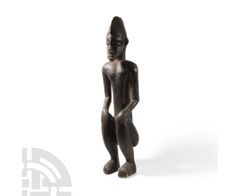 20th century A.D.. Depicted squatting and displaying scarification marks around the chest, median crested coiffure with hands