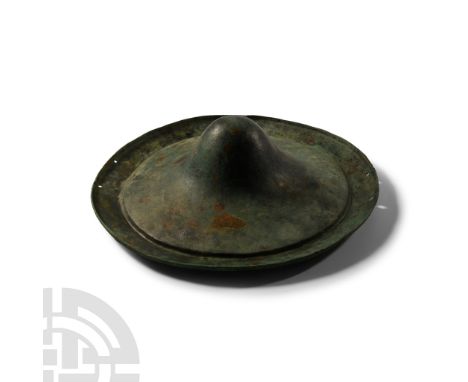 8th century B.C.. A hammered discoid shield raised from a single sheet, displaying a central conoid boss; two pairs of circul