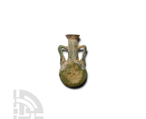 1st century A.D.. Amphoriskos with flat disc-shaped body, tubular neck with flared rim, two lateral knee-shaped handles to th
