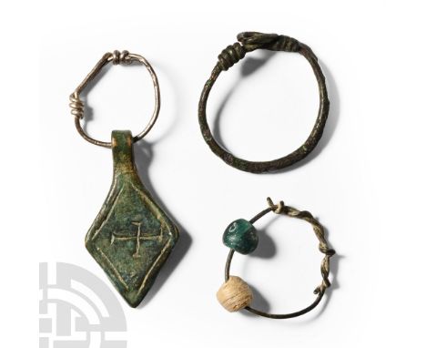 8th-11th century A.D.. Comprising: silver wire finger ring; silver wire loop with lozenge pendant, impressed cross potent; wi