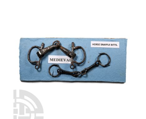 Circa 14th-16th century A.D.. Two snaffle bits with curb strap ring to each end, mounted on a fabric-covered display board wi