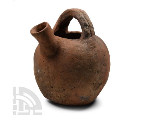 Middle-Late Bronze Age, 2nd-1st millennium B.C.. Barrel-shaped in profile with double-strap transverse handle, thick spout to